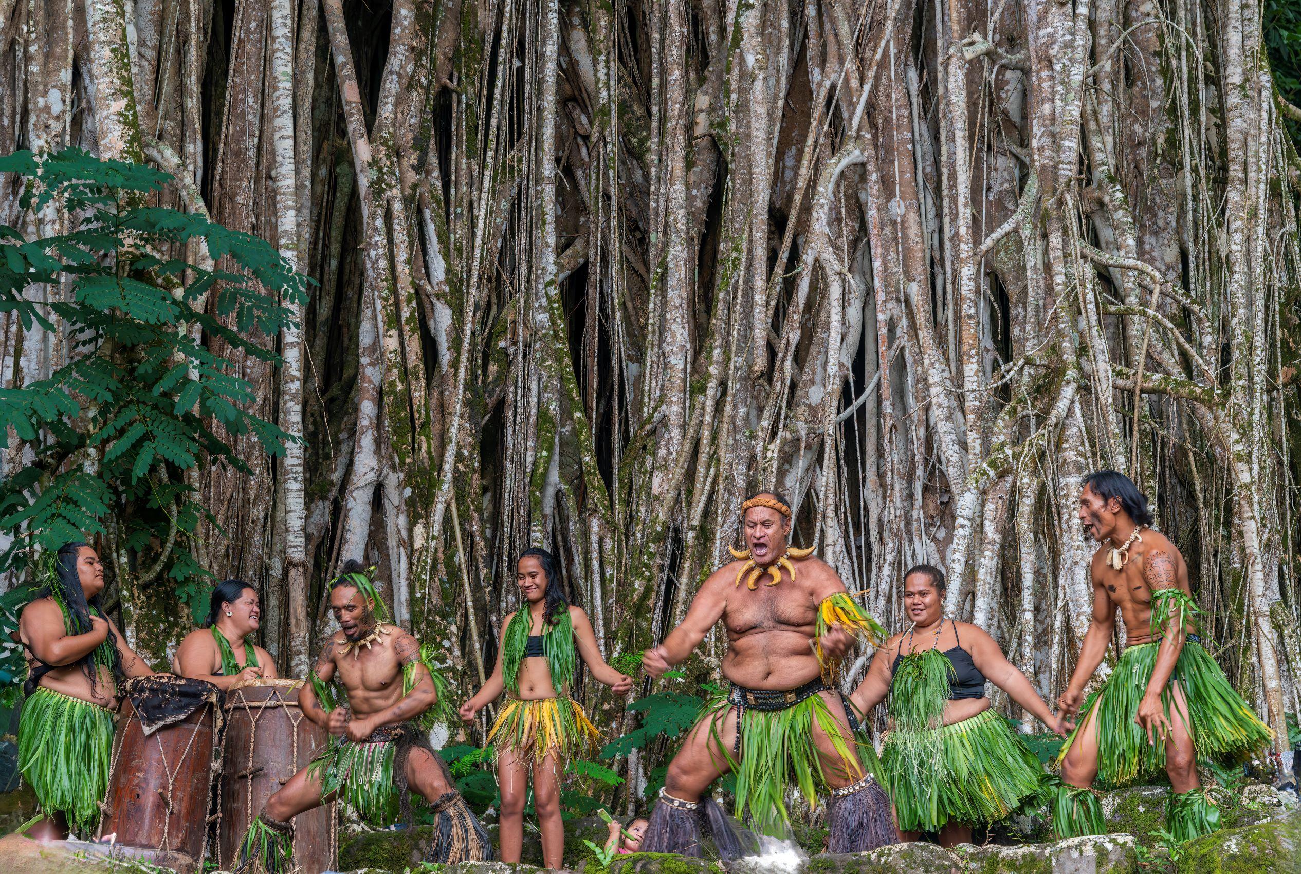 Wearing boar tusk choker necklaces and fern fronds, warrior-style dancers entertain by the giant banyan tree at the Kamuihei archeological site on Nuku Hiva. (Maria Coulson)