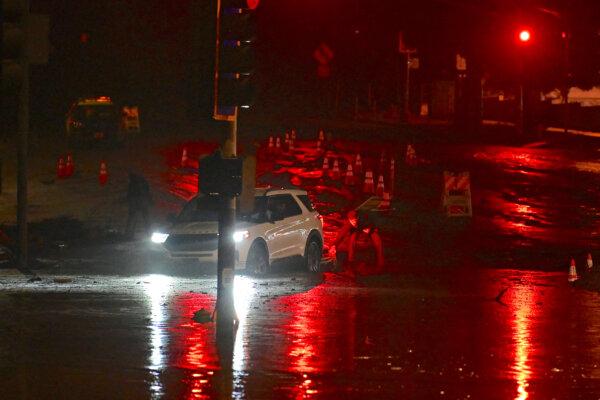 A motorist tries to escape the mud-covered intersection at Sunset Boulevard and Pacific Coast Highway, near the Palisades Fire zone, during a storm in Malibu, Calif., on Feb. 13, 2025. (Agustin Paullier/AFP via Getty Images)