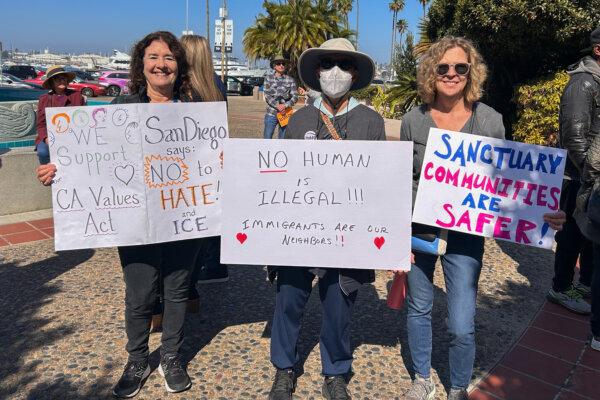 Maggie Baker (left) and other two protestors pose with signs after a press conference by California state Sen. Brian Jones when he announced SB 554, a new bill to overhaul state's sanctuary law, in front of the San Diego County Administration Building on Feb. 20, 2025. (Jane Yang/The Epoch Times)