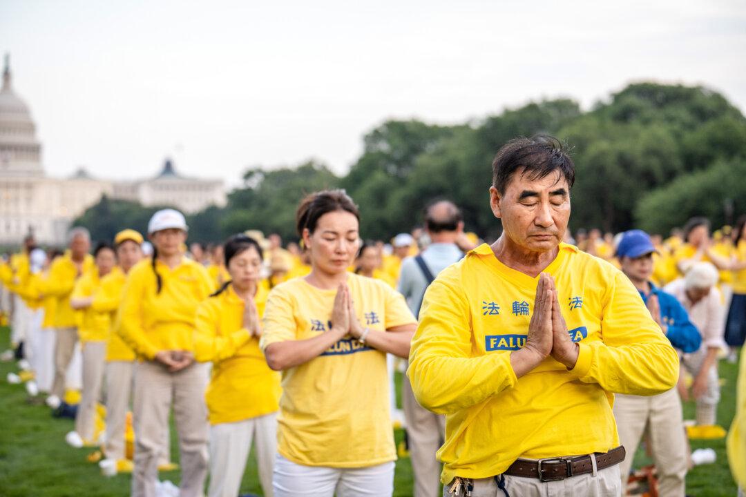 Falun Dafa practitioners practice exercises before taking part in a candlelight vigil commemorating practitioners who were persecuted to death by the Chinese Communist Party in China, in Washington on July 17, 2025. (Samira Bouaou/The Epoch Times)