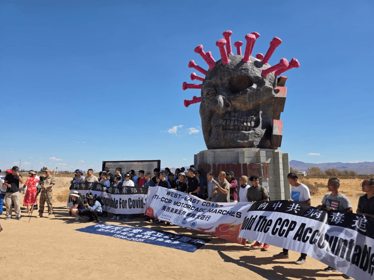 Cross-country car rally participants stand in front of the CCP Virus statue in Liberty Sculpture Park in the Mojave Desert town of Yermo, Calif., on Sept. 6, 2025. (Courtesy of Chen Weiming)