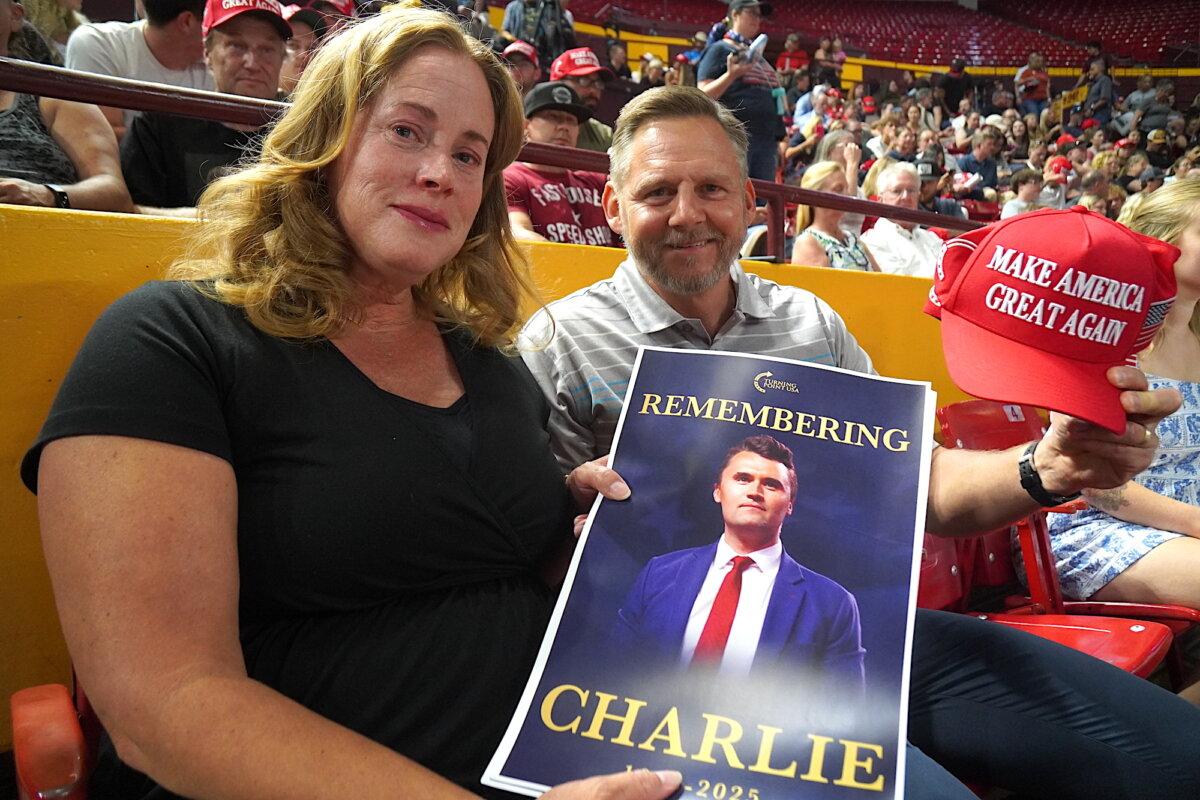 Denise and Bob Ruchala of Litchfield Park, Ariz., hold a picture of slain conservative youth leader Charlie Kirk and a Make America Great Again hat during a vigil in Tempe, Ariz., on Sept. 15, 2025. (Allan Stein/The Epoch Times)