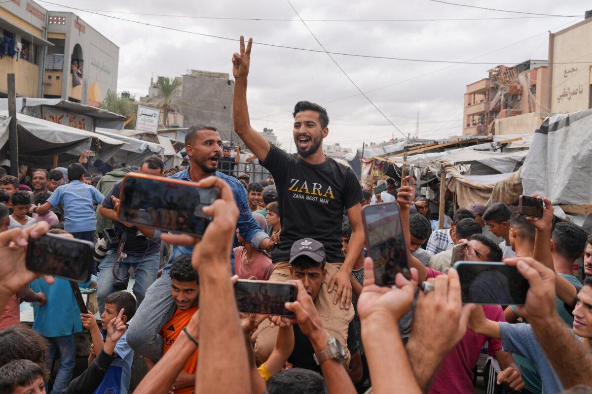 Palestinians celebrate following the announcement that Israel and Hamas have agreed to the first phase of a peace plan to pause the fighting, in Khan Younis, southern Gaza Strip, on Oct. 9, 2025. (AP Photo/Jehad Alshrafi)
