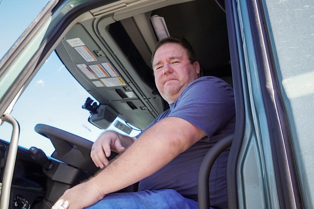 Truck driver Chris Hernandez, 45, sits in the cab of his tractor-trailer in Flagstaff, Ariz., on Oct. 19, 2025. Hernandez, who has driven trucks for 26 years, said he often encounters improperly trained foreign drivers on the road. (Allan Stein/The Epoch Times)