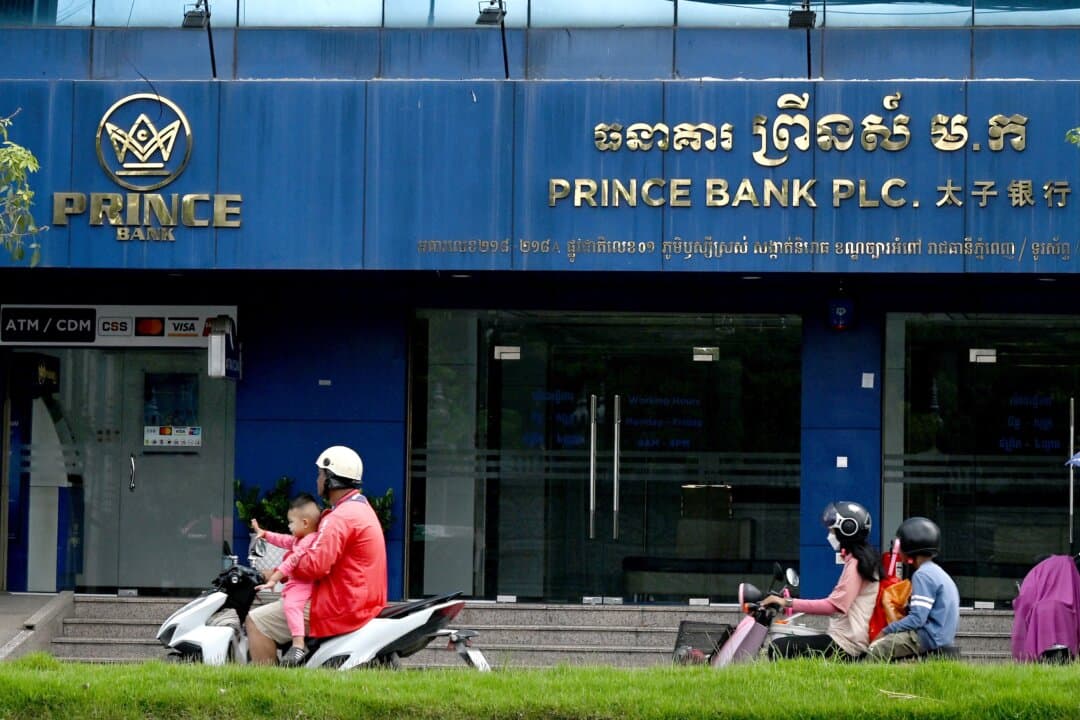 Motorists ride past a branch of the Prince Bank in Phnom Penh, Cambodia, on Oct. 15, 2025. The bank is part of Prince Holding Group, a multinational conglomerate founded by Chinese-born scam kingpin Chen Zhi, which the U.S. Justice Department says served as a front for "one of Asia's largest transnational criminal organizations." (Tang Chhin Sothy/AFP)