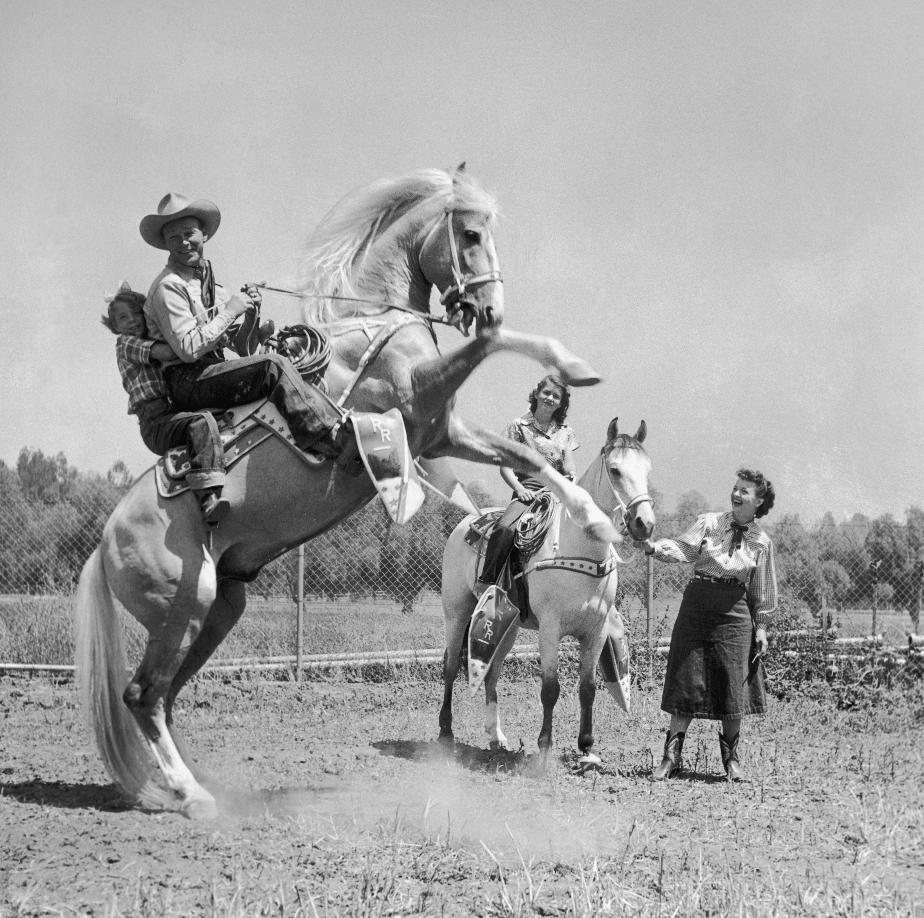 American actor and singer Roy Rogers sits in the saddle of a rearing horse with one of his daughters, as his older daughter rides a horse being led by his wife, American actor and singer Dale Evans, circa 1952. (Hulton Archive/Getty Images)