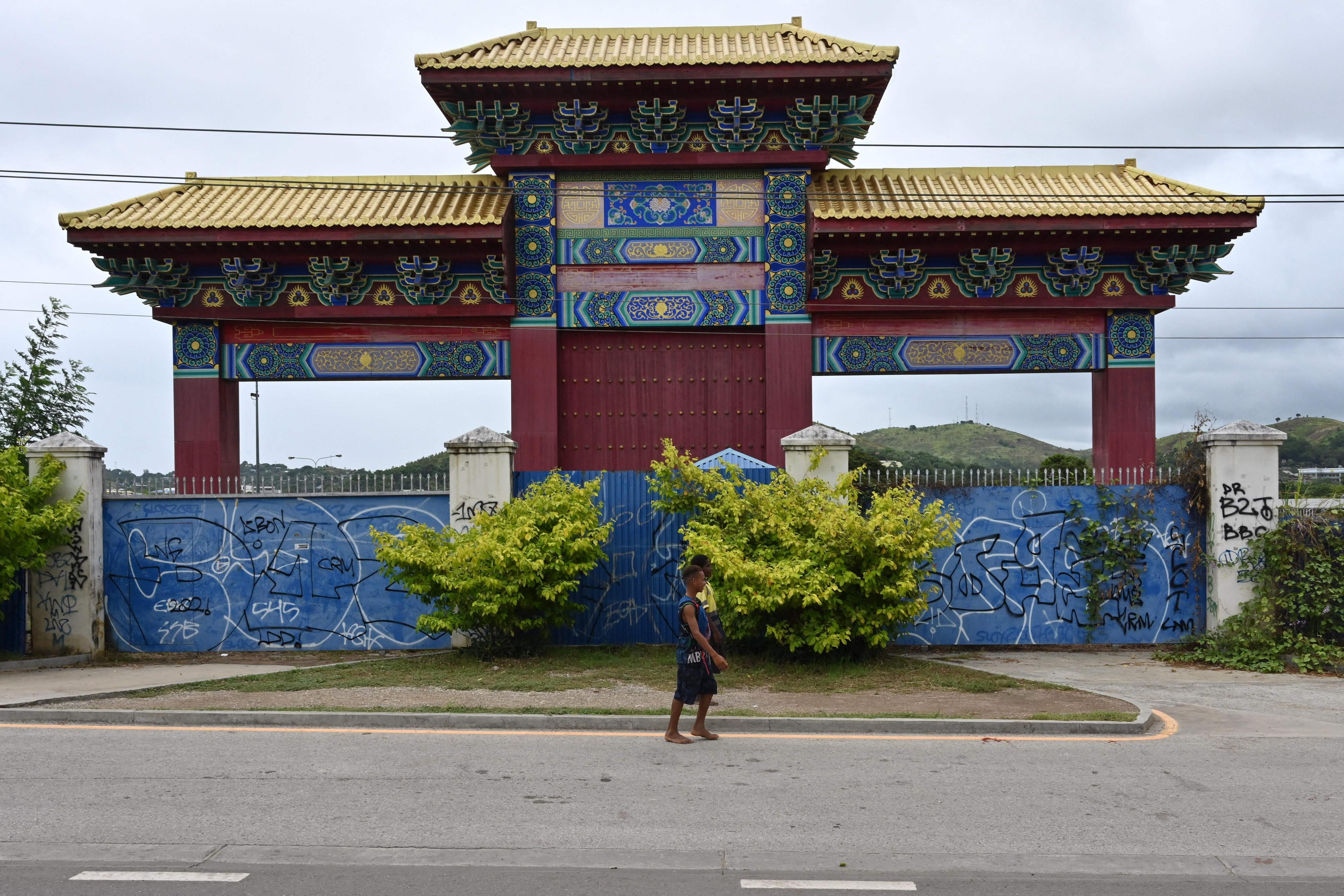 This picture taken on May 18, 2023 shows people walking past a Chinese style gate in front of a project site called Chinatown that stopped due to the COVID-19 pandemic in Port Moresby, Papua New Guinea. (Adek Berry/AFP via Getty Images)