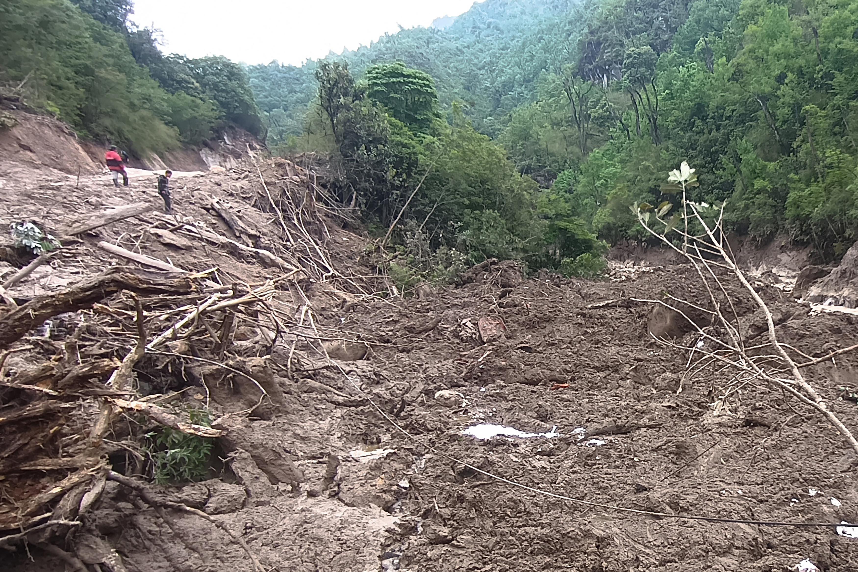 People (top L) stand next to debris in the aftermath of a landslide in a rare earth mining area in Pangwa in Myanmar's northern Kachin State on June 5, 2024. (STR/AFP via Getty Images)
