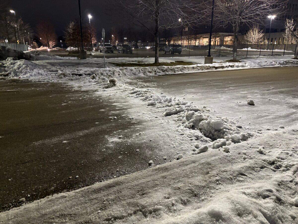 An anti-ICE protester attempted to pile snow on the road near the Bishop Henry Whipple Federal Building on Jan. 9, 2026, as an attempt to make it harder for law enforcement to exit the area. (Nathan Worcester/The Epoch Times)