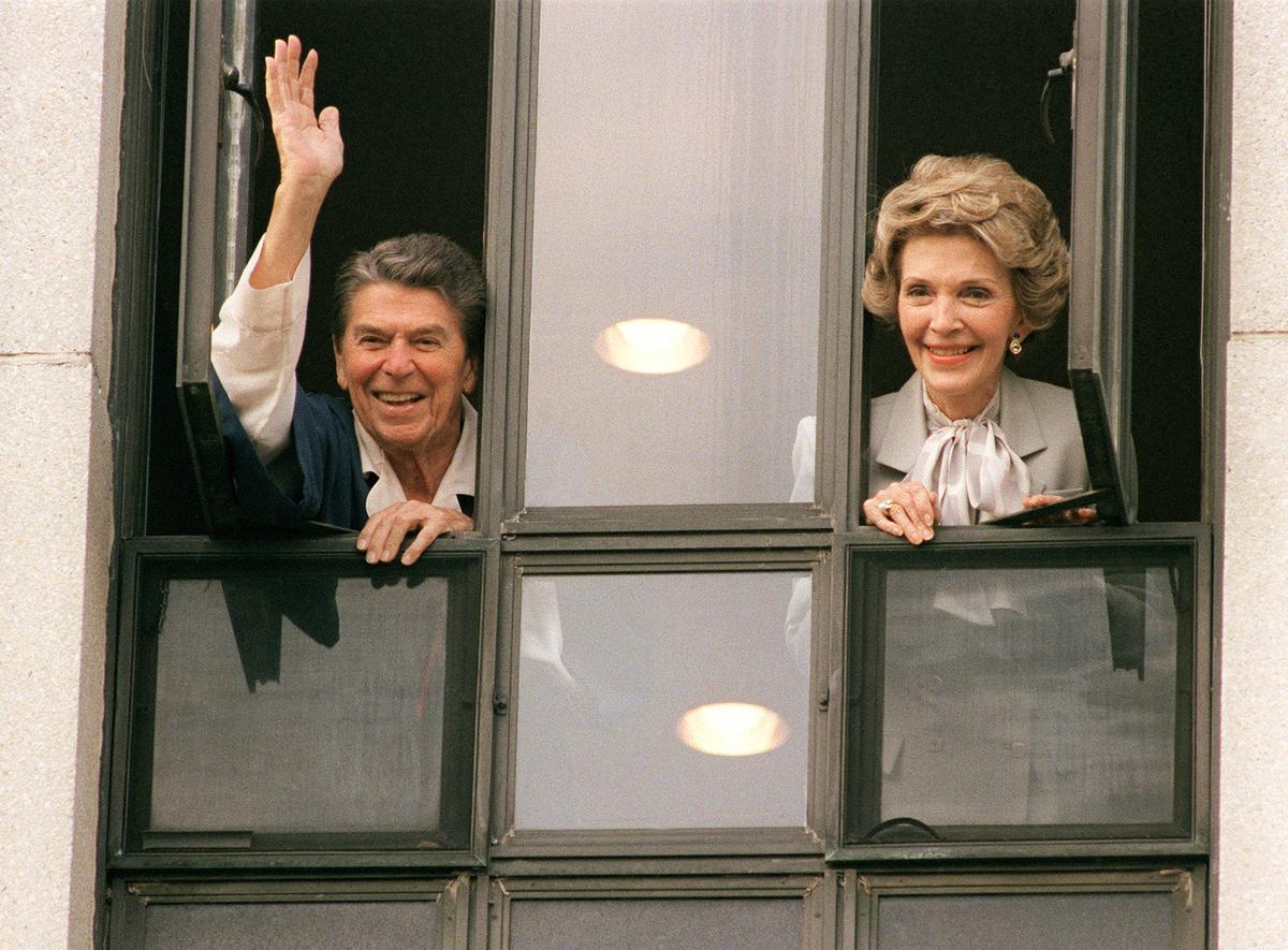 Ronald and Nancy Reagan greet reporters from the window of his room at Bethesda Naval Hospital, where he had undergone surgery the day before, on Jan. 6, 1987. (MIKE SARGENT/AFP/Getty Images)