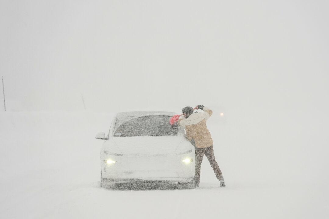 A motorist scrapes ice off his vehicle along Interstate 80 during a snowstorm near Camp Spaulding in Placer County, Calif., on Feb. 19, 2026. (Godofredo A. Vásquez/AP Photo)