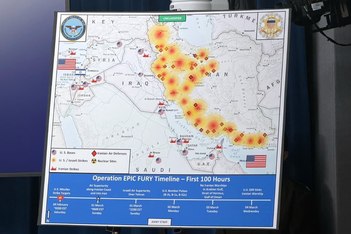 A Department of War map titled "Operation EPIC FURY Timeline—First 100 Hours" is displayed during a news conference with War Secretary Pete Hegseth and Chairman of the Joint Chiefs of Staff Gen. Dan Caine at the Pentagon in Washington on March 4, 2026. (Konstantin Toropin/AP Photo)