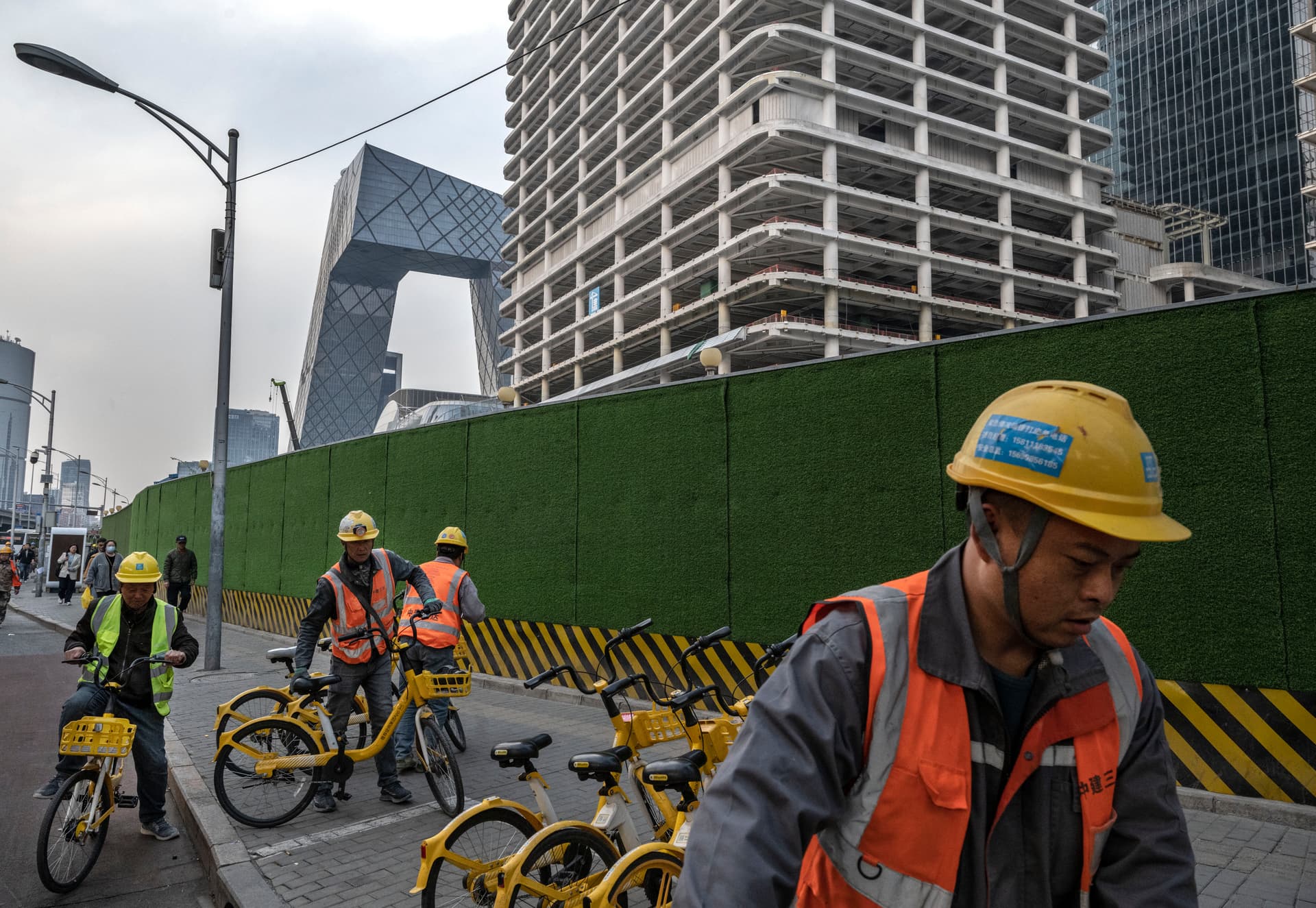 Construction workers rent shared bicycles as they leave a building site for a new office tower in the Central Business District of Beijing on April 3, 2025. (Kevin Frayer/Getty Images)