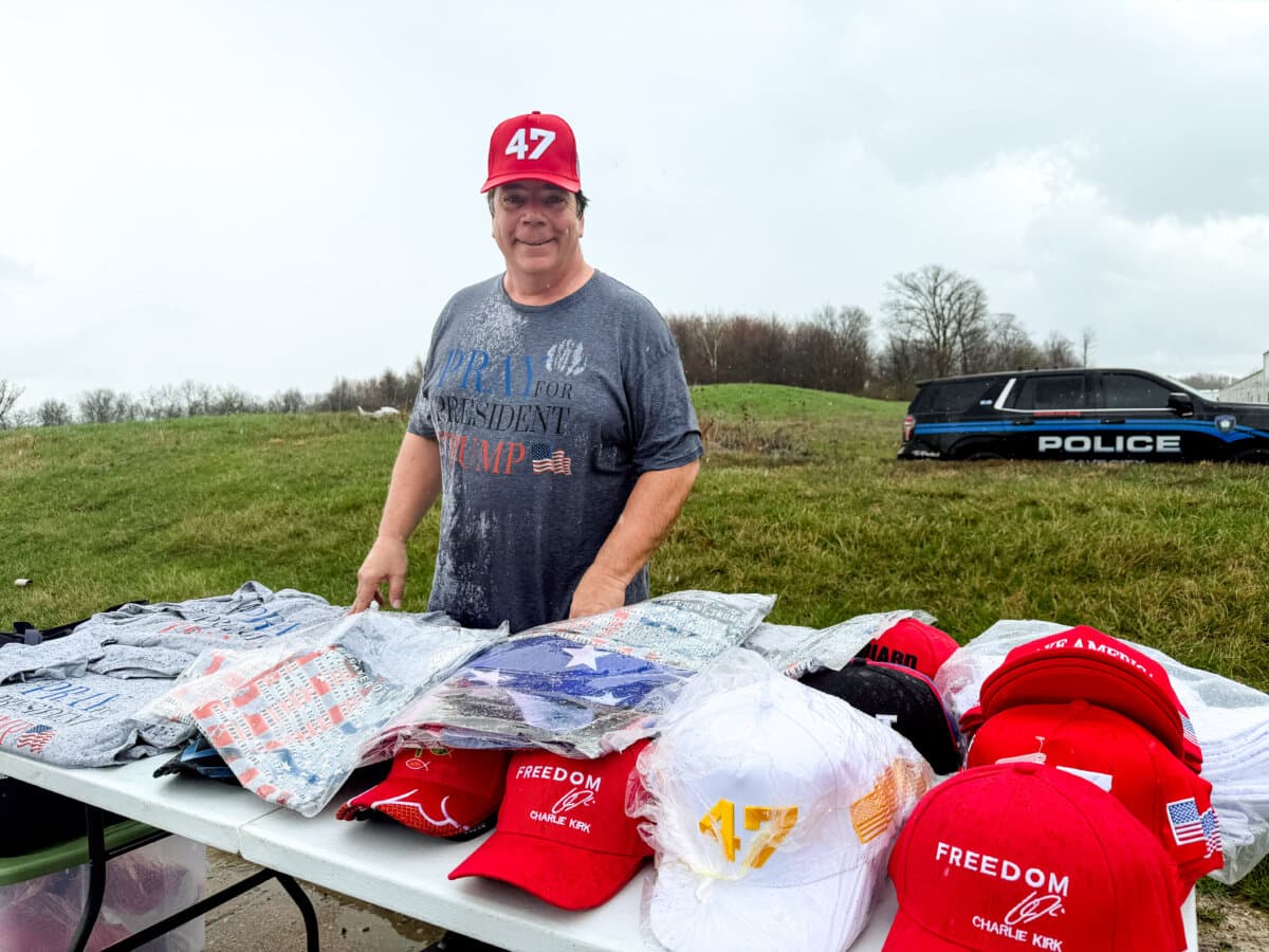 Kentucky resident Rick Homer, 61, stands in the rain, selling T-shirts that said “Pray for President Trump” outside Verst Logistics in Hebron, Ky., on March 11, 2026. (Janice Hisle/The Epoch Times)