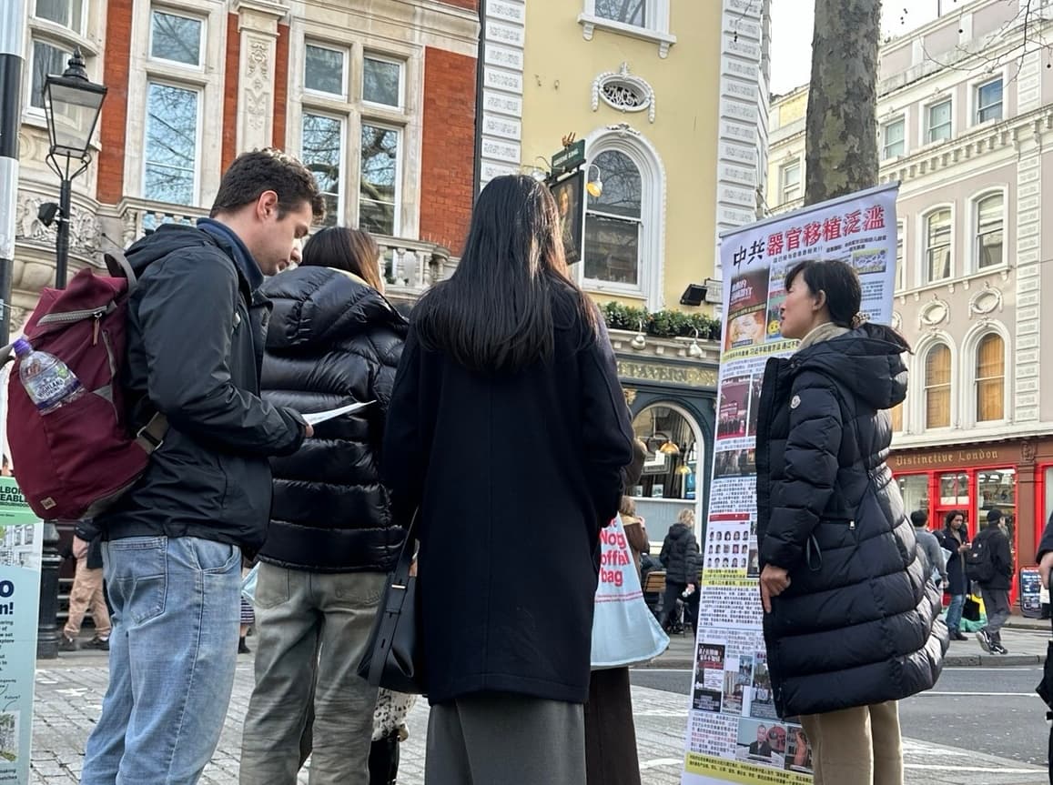 Zhang Chunping (R) talks to tourists beside a poster about the forced organ harvesting in China, near the British Museum in London. (Courtesy of Zhang Chunping)