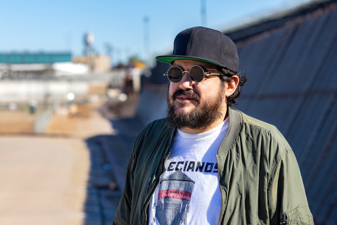 Joseph Guilin, a Calexico, Calif., resident, stands near the U.S.–Mexico border wall in El Centro, Calif., on Jan. 19, 2026. With fewer illegal border crossings in town, Guilin said tax dollars should be directed toward economic development to revitalize the local business district rather than to house illegal immigrants. (John Fredricks/The Epoch Times)
