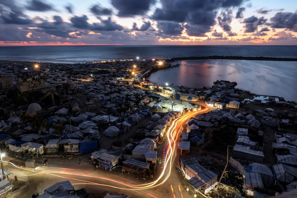 This long exposure photograph shows trails from vehicles moving along alleys past tents sheltering people displaced by war around the seaport in Gaza City, Gaza, on March 26, 2026. (Omar Al-Qattaa/AFP via Getty Images)
