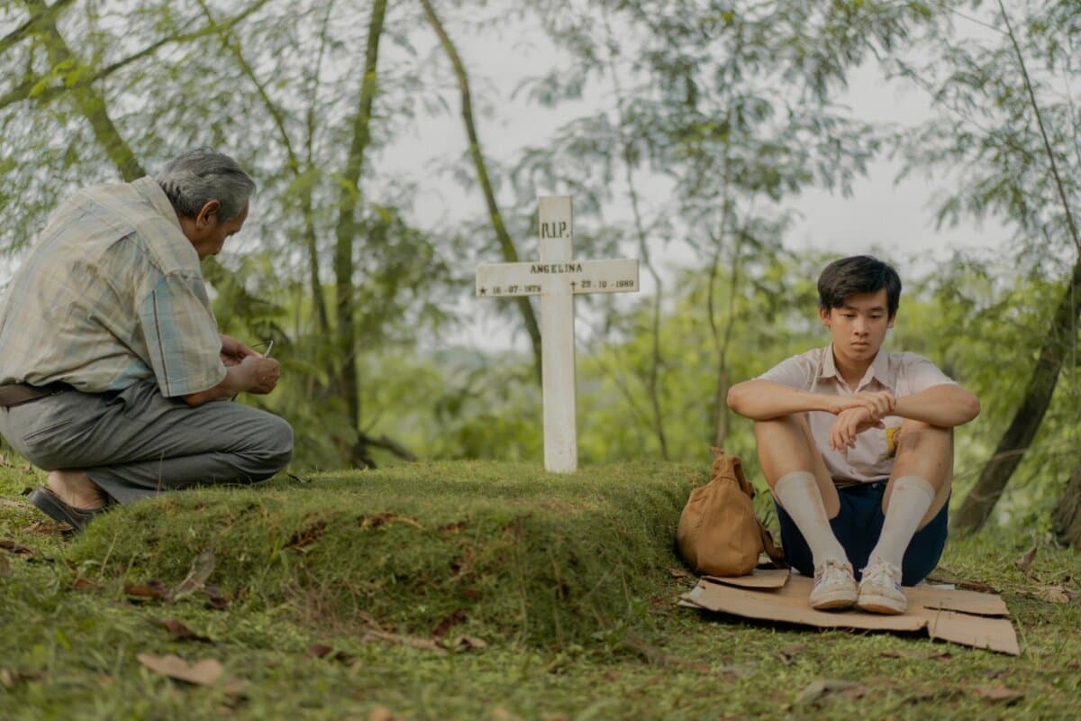 Simon Ferdinan (Agus Wibowo) and Kefas (Millo Taslim) sit in a cemetery, in "A Letter to My Youth." (Netflix)