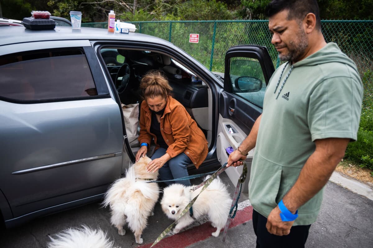 People tend to their pets outside Freedom Hall, an evacuation center in Fountain Valley, Calif., on May 25, 2026. (AP Photo/Ethan Swope)