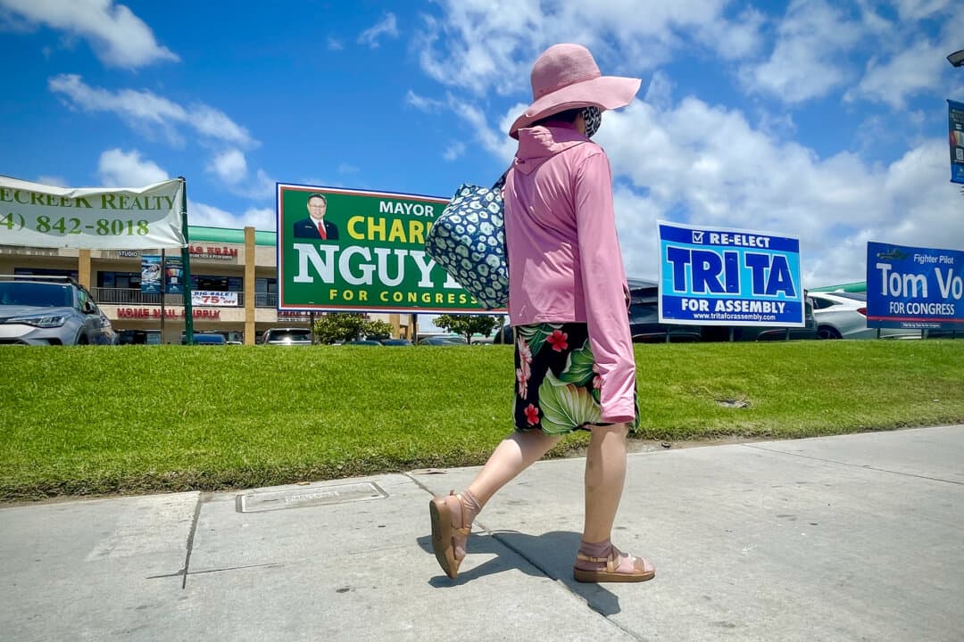 A woman walks near 45th Congressional District primary campaign signs near the Little Saigon neighborhood in Westminster, Calif., on May 27, 2026. (Beige Luciano-Adams/The Epoch Times)