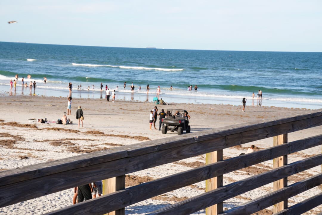 Police are seen afar breaking up a fight during a planned takeover in Jacksonville Beach, Fla., on June 6, 2026. Teen takeovers have disrupted cities across the country with chaotic and often violent incidents; several firearms were recovered during recent gatherings in Jacksonville Beach. (Troy Myers/The Epoch Times)