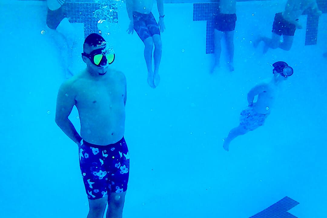 (Top Left) A trainee swims underwater with his hands behind his back, at Deep End Fitness Scottsdale, Ariz., on May 21, 2026. (Top Right) A trainee slowly exhales as he move to the surface of a 14-foot-deep pool. (Bottom Left) Students train with their hands behind their backs to build endurance in the deep water pool. Several trainees are preparing to join military service. (Bottom Right) A trainee glides through the water at the Eldorado Aquatic Center in Scottsdale, Ariz., on May 21, 2026. (Allan Stein/The Epoch Times)