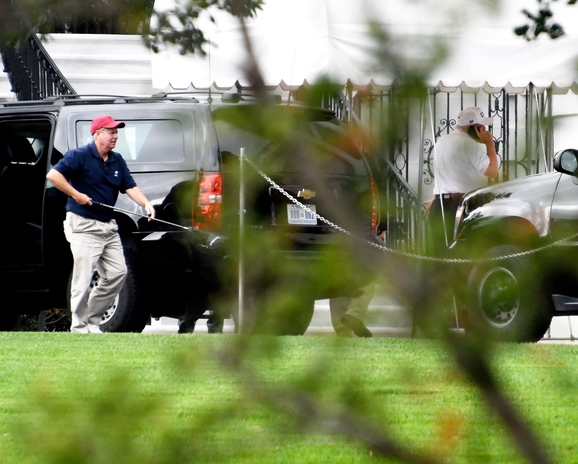 Sen. Lindsey Graham (R-S.C.) (L) carries one of his golf clubs as he leaves the presidential limo at the White House on Oct. 14, 2017. (Ron Sachs - Pool/Getty Images)
