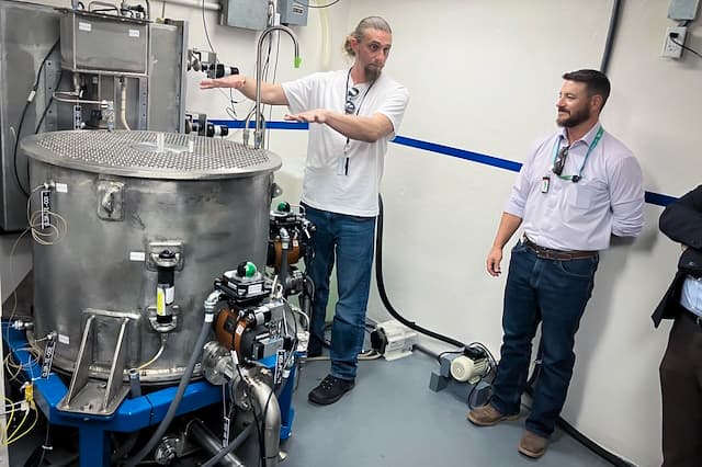 Deployable Energy's Chief Operating Officer Lance Maul explains how the company’s Unity reactor, hauled from Texas to Idaho in a Ford F-150 bed, uses 696 uranium rods in a 63-gallon tub-like container to generate electricity, at Idaho National Laboratory, west of Idaho Falls, Idaho, in June 2026. (John Haughey/The Epoch Times)