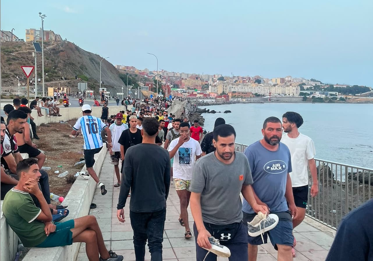 Moroccan migrants walk the coastal road near Avenida Martínez Catena in the Spanish territory of Ceuta on July 31, 2026. (Etienne Fauchaire/The Epoch Times)
