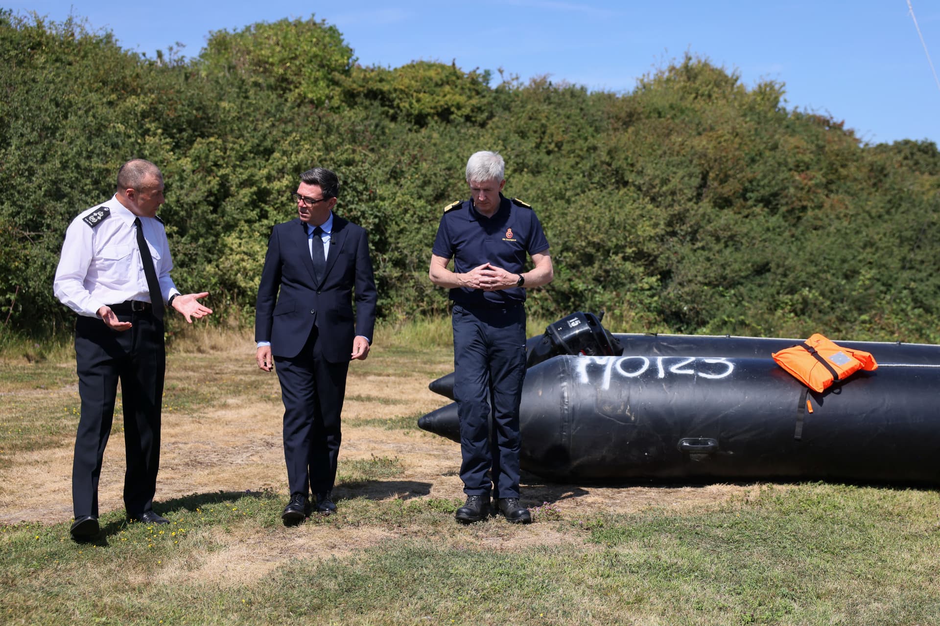 British Prime Minister Andy Burnham (C) speaks with John Craig, interim chief coastguard, and Duncan Capps, border security commander (L), near a recovered small boat, which was used by illegal immigrants crossing the English Channel, during a visit to HM Coastguard Maritime Rescue Coordination Centre, in Dover, England, on Aug. 2, 2026. (Jack Taylor/Pool Photo via AP)