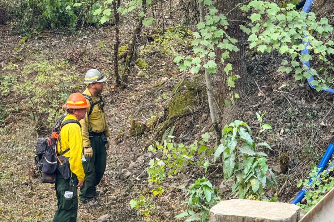 (Top) Public information officer Jim Bartlett identifies on a map where containment efforts were happening in relation to the rest of the Paradise fire, along Mill Creek in northeastern Oregon on Aug. 26, 2026. (Bottom Left) Firefighters scan a hillside near Mill Creek in northeast Oregon on Aug. 26, 2026. (Bottom Right) Sprinklers attack the slow-moving extent of the Paradise fire as it tries to make its way to the bank of Mill Creek in northeast Oregon on Aug. 26, 2026. (T.J. Muscaro/The Epoch Times)