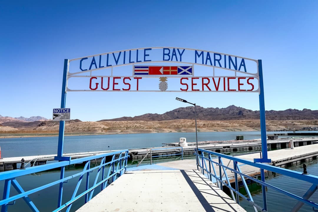 (Top) Motorboats near a jetty at Lake Mead’s Hemenway Harbor, near Boulder City, Nev., on Aug. 27, 2026. (Bottom Left) The entrance to Callville Bay Marina at Lake Mead on Aug. 27, 2026. (Bottom Right) An electric sign advises boaters of a ramp closure at Callville Bay Marina on Aug. 27, 2026. (Allan Stein/The Epoch Times)