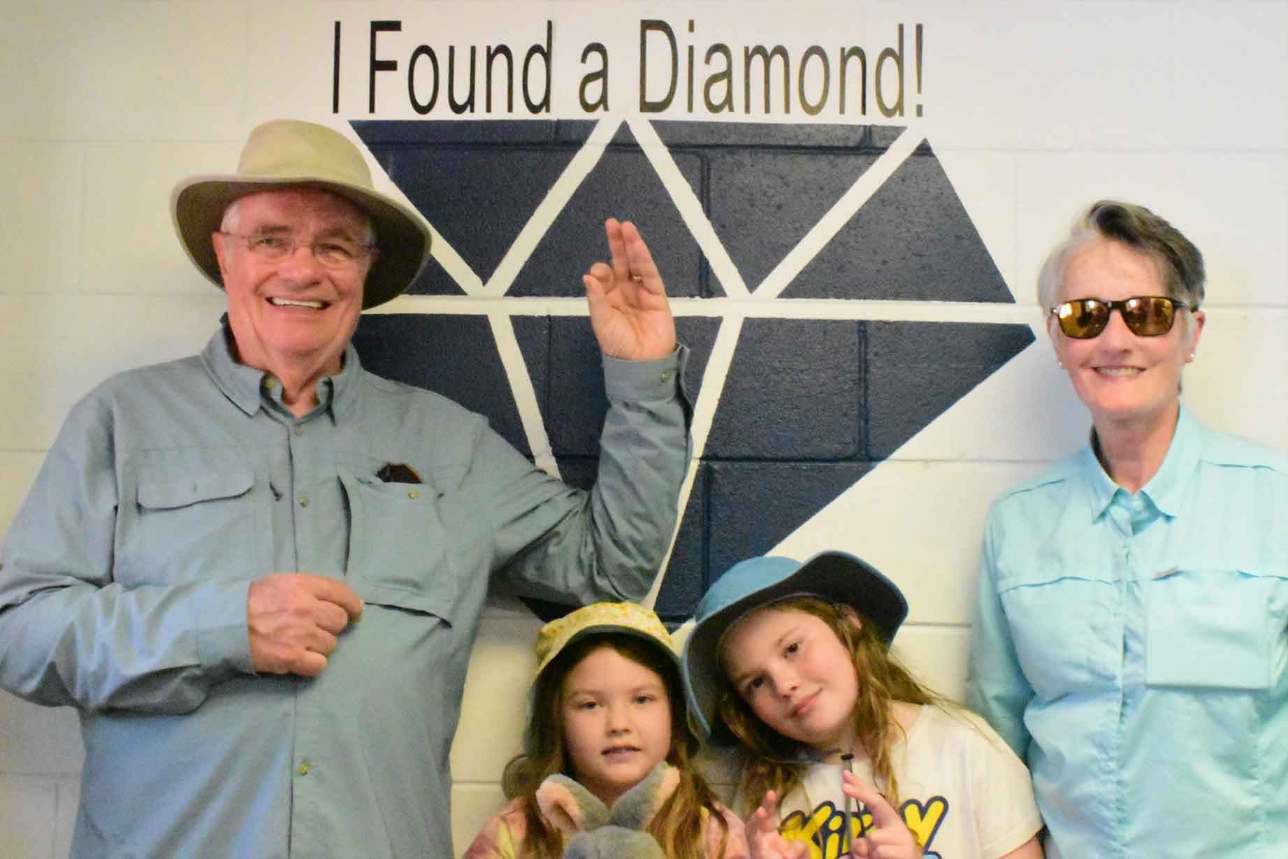 Barry Smith, his wife, and their two granddaughters pose with the diamond he found at Crater of Diamonds State Park on Aug. 16, 2026. (Crater of Diamonds State Park)