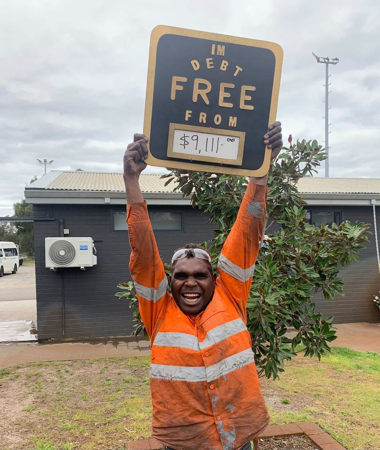 A male resident at Shalom House holds a sign showing that he is debt free. (Courtesy of Shalom House)