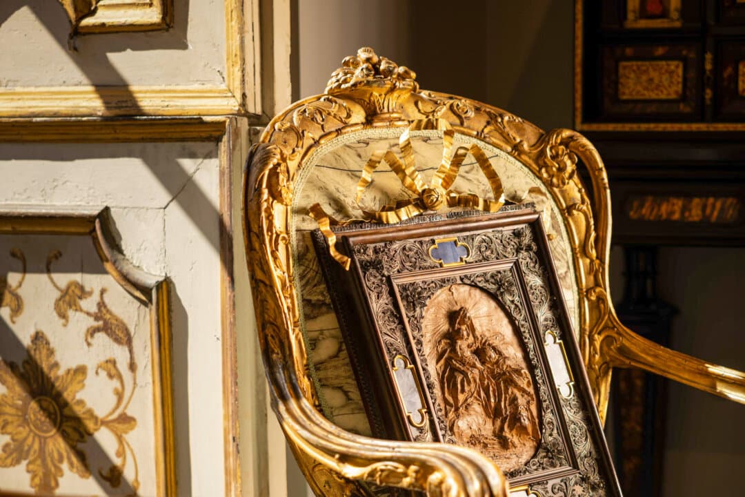 (Top) Gallery stalls line a wing of the Palazzo Corsini during the 34th International Biennial of Antiques in Florence, Italy, in September 2026. (Bottom Left) A framed, hand-carved wooden artwork featuring the Florentine inlaid “pietre dure” technique is displayed with an ornate antique chair at the 34th International Biennial of Antiques in Florence, Italy, in September 2026. (Bottom Right) Jean-Baptiste Oudry’s “The Fisherman and the Little Fish,” signed and dated 1739, is displayed by Voena gallery at the 34th International Biennial of Antiques in Florence, Italy, in September 2026. (Dario Borruto)