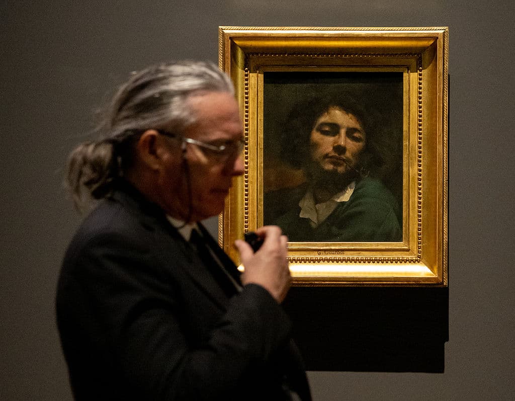 A security man walks past the self-portrait of the French painter Gustave Courbet, "Man with a Pipe," during the opening of the first solo exhibition dedicated to Gustave Courbet (1819-1877) at the Leopold Museum in Vienna, Austria on Feb. 18, 2026. (Joe Klamar/AFP via Getty Images)