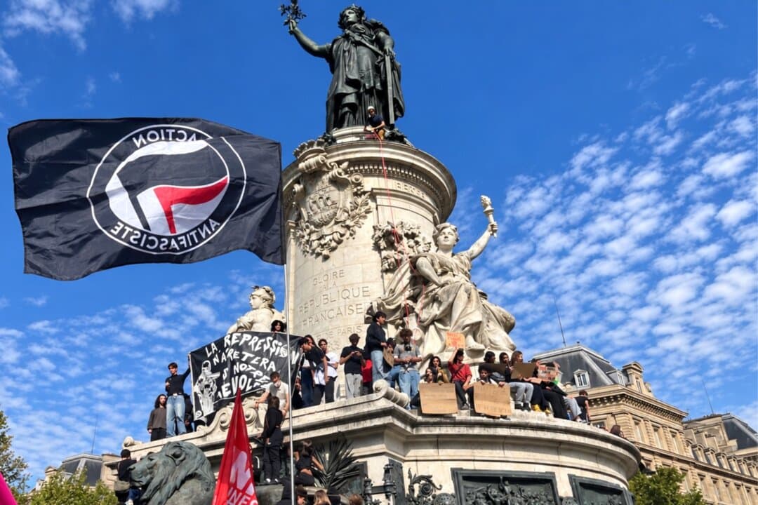 Tear gas drifts across Place de la Nation at the end of a Paris high school march from Place de la République, France, on Oct. 6, 2026. Students carried the Antifa flag. (Etienne Fauchaire/The Epoch Times)