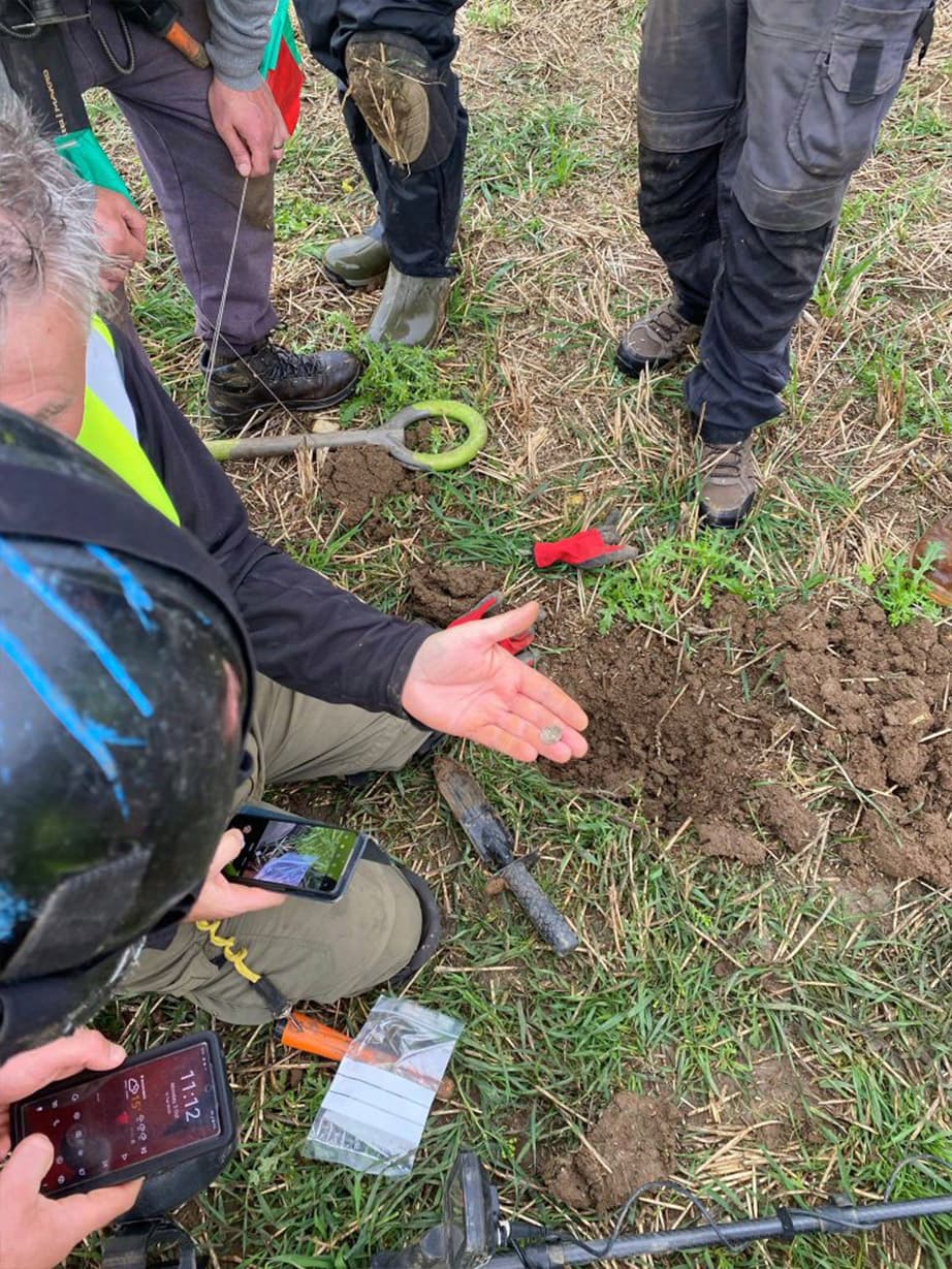 Metal detectorists examine a silver coin plucked from a field in Bickmarsh, UK. (Worcestershire Archive and Archaeology Service)