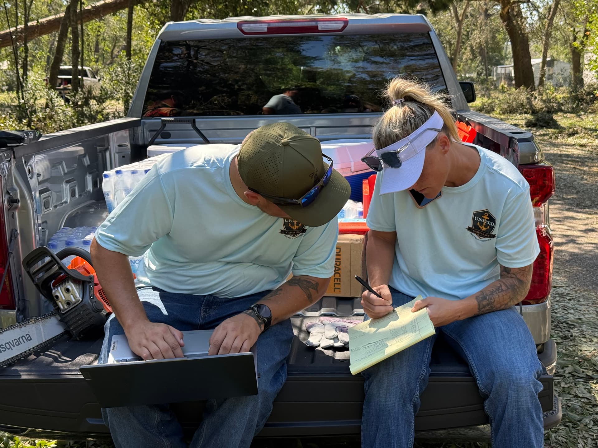 United Cajun Navy volunteers Mason Adcock (L) and Keisha Boyd (R) receive and log requests for aid on site in Bagdad, Fla., on Oct. 11, 2026. (T.J. Muscaro/The Epoch Times)