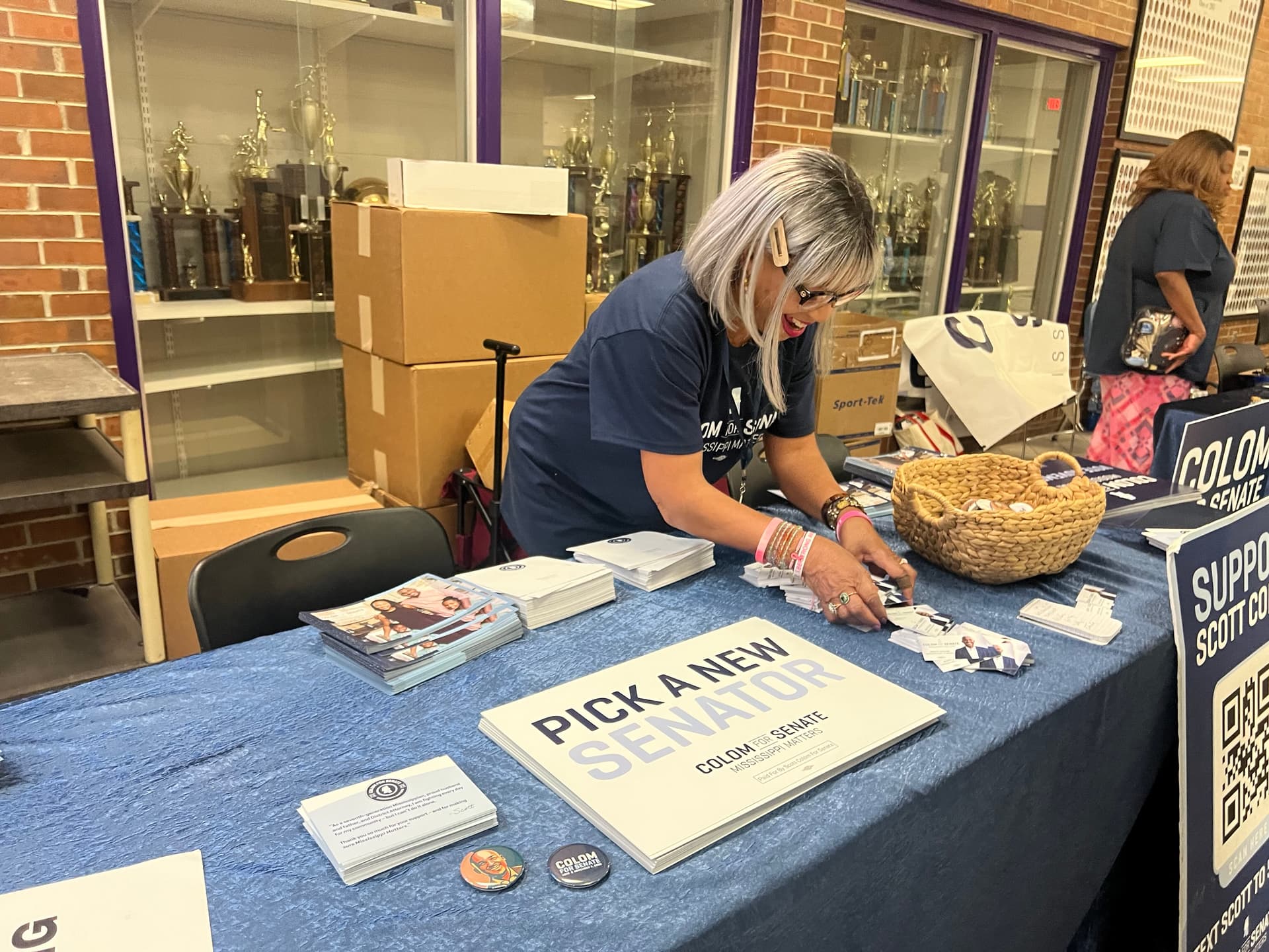 Scott Colom’s campaign handed out signs, buttons, and brochures to attendees of a rally at Columbus High School, Miss., on Oct. 22, 2026. (Jacki Thrapp/The Epoch Times)