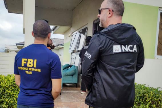 Officers from the FBI and the UK's National Crime Agency wait outside a suspected scam center in Ghana, in this file photo. (FBI, National Crime Agency)