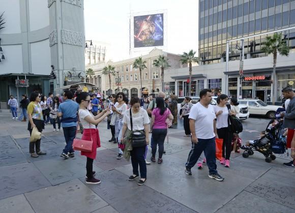 Tourists get their pictures taken on top of hand and foot print of Hollywood movie stars at TCL Chinese Theatre in Los Angeles, Calif. on Dec. 7, 2015. (Photo by Kevork Djansezian/Getty Images)