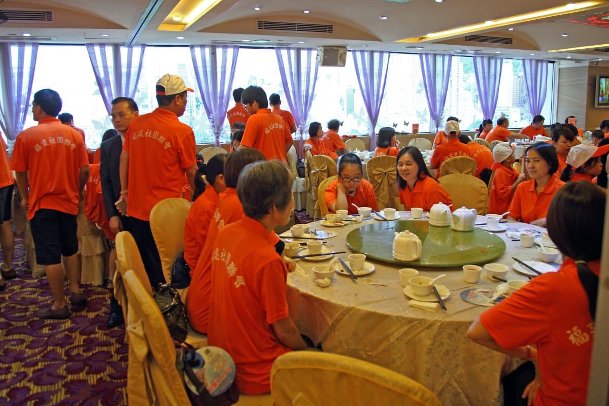 Protesters in T-shirts with “Hong Kong Federation of Fujian Associations” printed on the back enjoy a restaurant meal as a bribe for joining the recent anti-democracy march in Hong Kong on Aug. 17, 2014. Pro-CCP groups booked an entire Cantonese restaurant to give feasts to participants. (The Epoch Times)