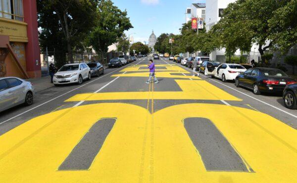 A man crosses over a giant street mural reading "Black Lives Matter" spanning three city blocks near City Hall in San Francisco, Calif., on June 12, 2020. (Josh Edelson/AFP via Getty Images)