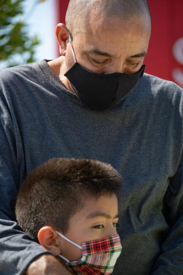 Francisco Esquival and his son, Matthew, pray with a Saddleback Church volunteer at the pop-up food donation site at Savanna High School in Anaheim, Calif., on Aug. 18, 2020. (John Fredricks/The Epoch Times)