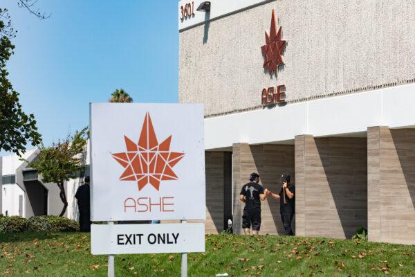 Two men connect fists in front of ASHE Society cannabis shop in Santa Ana, Calif., on Aug. 14 2020. (John Fredricks/The Epoch Times)