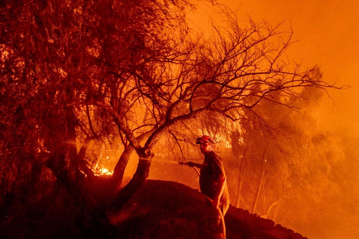 Bruce McDougal hoses down vegetation while working to save his home from the Bond Fire burning though the Silverado community in Orange County, Calif., on Dec. 3, 2020. (Noah Berger/AP Photo)
