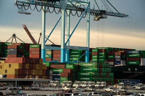 Shipping containers are stacked below a crane at the Port of Los Angeles on Jan. 12, 2021. (John Fredricks/The Epoch Times)