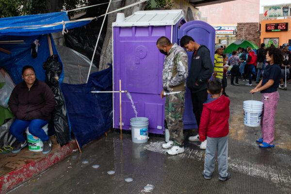 Migrants wait for water at the El Chaparral encampment in Tijuana, Mexico, on April 22, 2021. (John Fredricks/The Epoch Times)