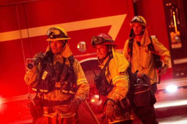 Firefighters watch flames burst from a propane tank as the Dixie Fire tears through the Indian Falls community in Plumas County, Calif., on July 24, 2021. (Noah Berger/AP)
